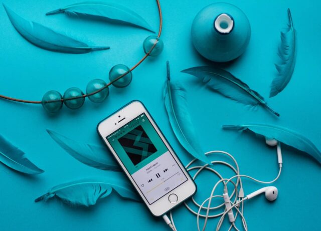 Cómo escuchar música por internet gratis en el móvil 9 iPhone with EarPods beside feathers