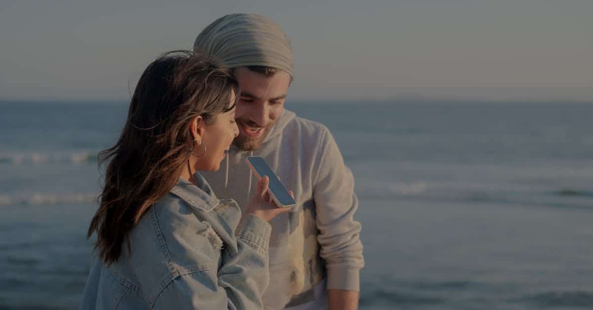 Madrid y el nuevo código de las citas: por qué la capital lidera la revolución de los encuentros digitales en España 1 A couple enjoys a conversation by the sea on a windy day, captured in a serene moment.